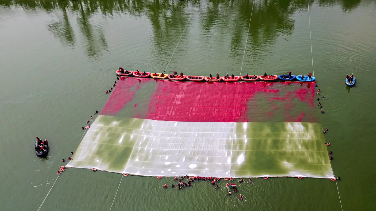 Foto udara relawan membentangkan bendera Merah Putih di Situ Gintung, Tangerang Selatan, Banten, Senin (17/8/2026). (Hanung Hambara/Jawa Pos)