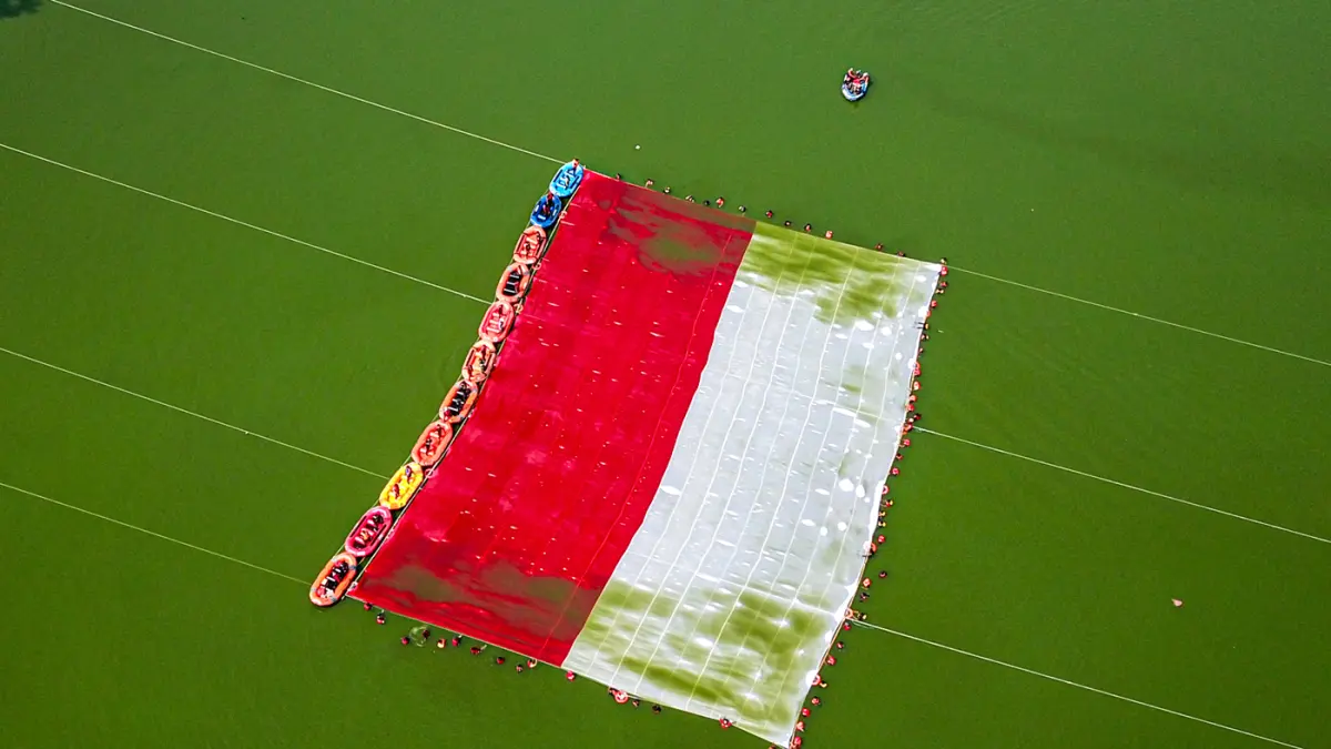 Foto udara relawan membentangkan bendera Merah Putih di Situ Gintung, Tangerang Selatan, Banten, Senin (17/8/2026). (Hanung Hambara/Jawa Pos)