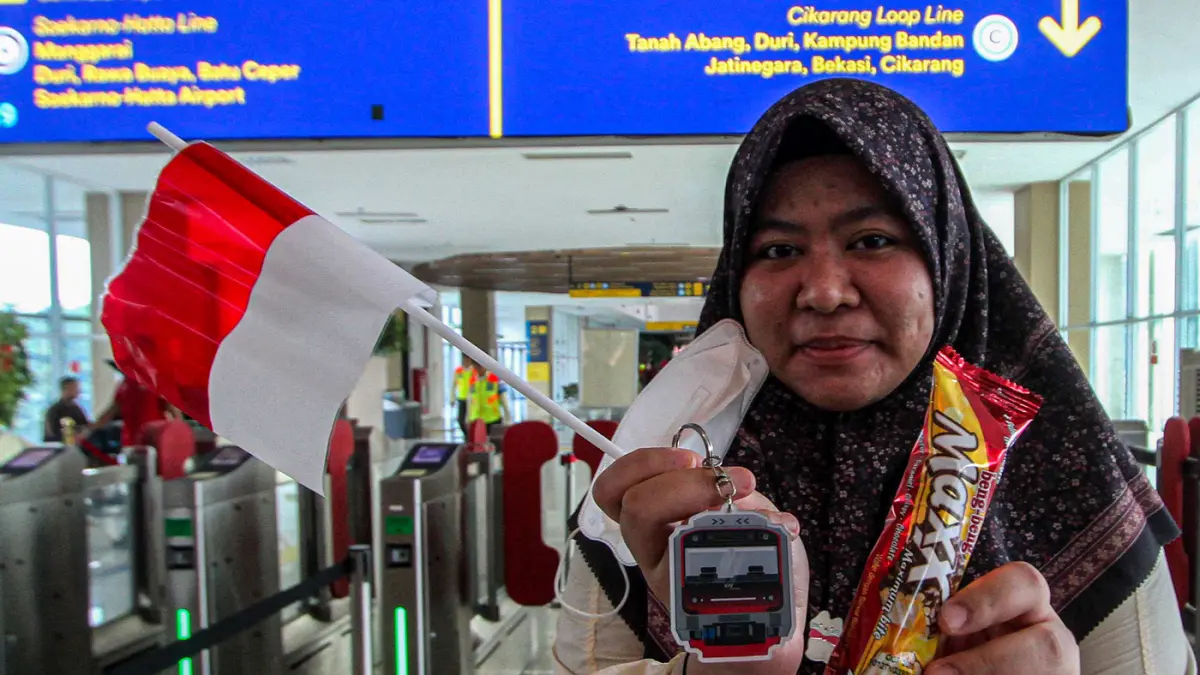 Petugas memberikan bendera merah putih kepada calon penumpang di stasiun BNI City, Jakarta, Senin (17/8/2026). (Salman Toyibi/Jawa Pos)