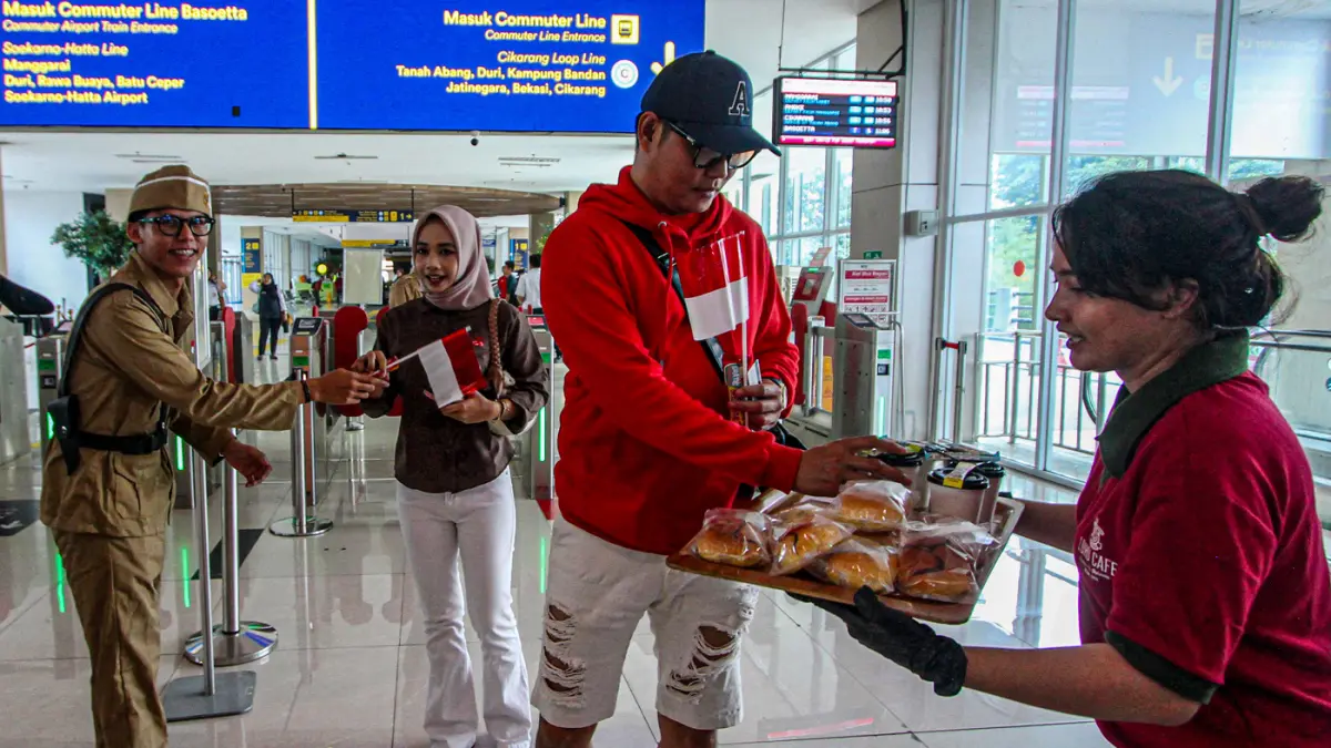 Petugas memberikan bendera merah putih kepada calon penumpang di stasiun BNI City, Jakarta, Senin (17/8/2026). (Salman Toyibi/Jawa Pos)