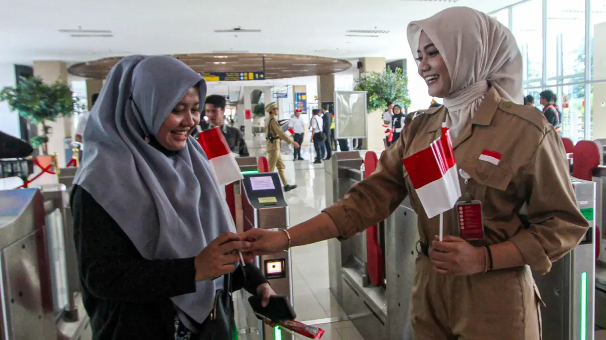 Petugas memberikan bendera merah putih kepada calon penumpang di stasiun BNI City, Jakarta, Senin (17/8/2026). (Salman Toyibi/Jawa Pos)