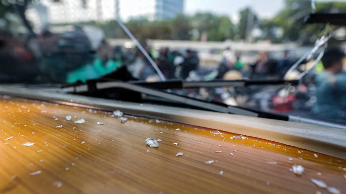 Serpihan kaca mobil bus Aliansi Masyarakat Pati Bersatu (AMPB) yang pecah dilempar orang tidak di kenal di depan Kompleks Parlemen, Senayan, Jakarta, Senin (24/8/2026). (Hanung Hambara/Jawa Pos)