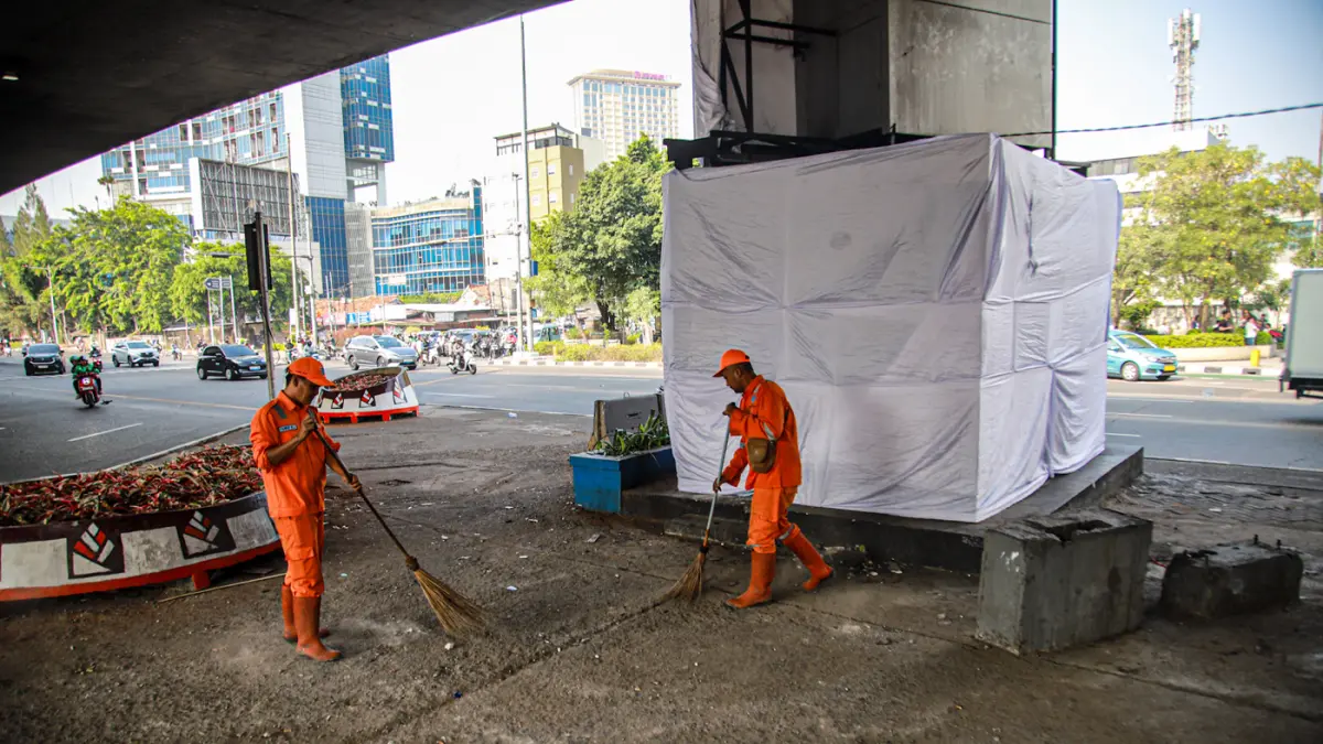 Anggota PPSU membersihkan sampah di samping pos polisi yang dibakar di Jalan KS. Tubun, Jakarta, Jumat (28/08/2026). (Hanung Hambara/Jawa Pos)