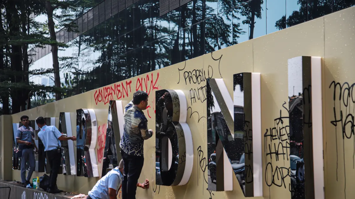 Pegawai Bank BNI membersihkan tembok yang terkena vadalisme usai demo kemarin di Menara BNI Pejompongan, Jalan Penjernihan, Jakarta, Jumat (28/08/2026). (Hanung Hambara/Jawa Pos)