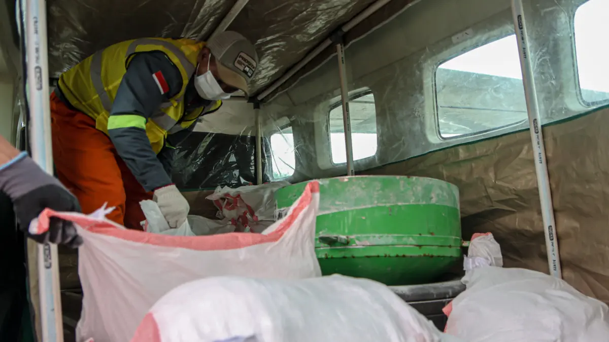 Petugas darat memasukan garam untuk penyemaian garam (NaCl) saat Operasi Modifikasi Cuaca (OMC) di Bandara Pondok Cabe, Pamulang, Tangerang Selatan, Selasa (22/09/2026). (Hanung Hambara/Jawa Pos)