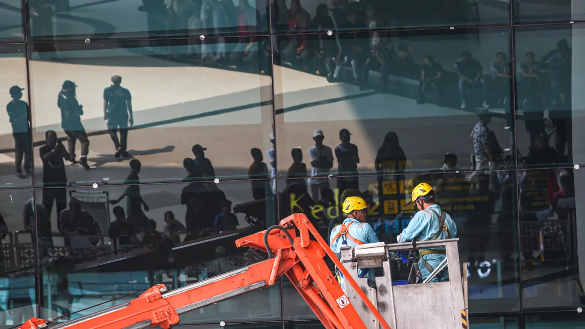 Pekerja gedung membersihkan kaca fasad menggunakan crane di Terminal 3, Bandara Soekarno-Hatta, Tangerang, Rabu (23/09/2026). (Hanung Hambara/ Jawa Pos)