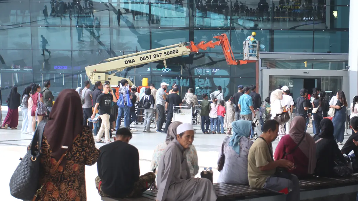 Pekerja gedung membersihkan kaca fasad menggunakan crane di Terminal 3, Bandara Soekarno-Hatta, Tangerang, Rabu (23/09/2026). (Hanung Hambara/ Jawa Pos)