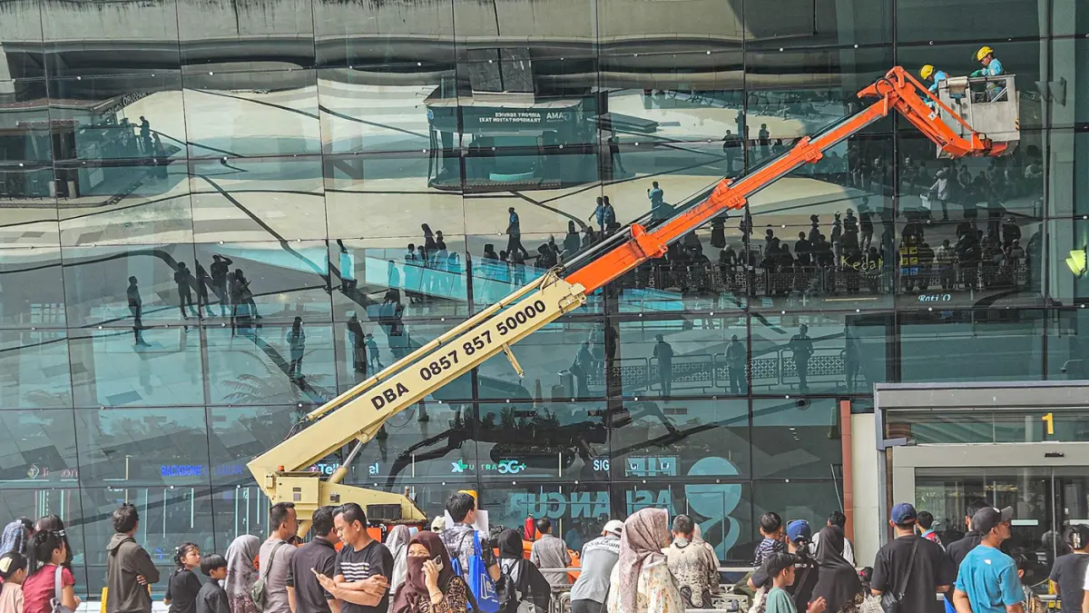 Pekerja gedung membersihkan kaca fasad menggunakan crane di Terminal 3, Bandara Soekarno-Hatta, Tangerang, Rabu (23/09/2026). (Hanung Hambara/ Jawa Pos)