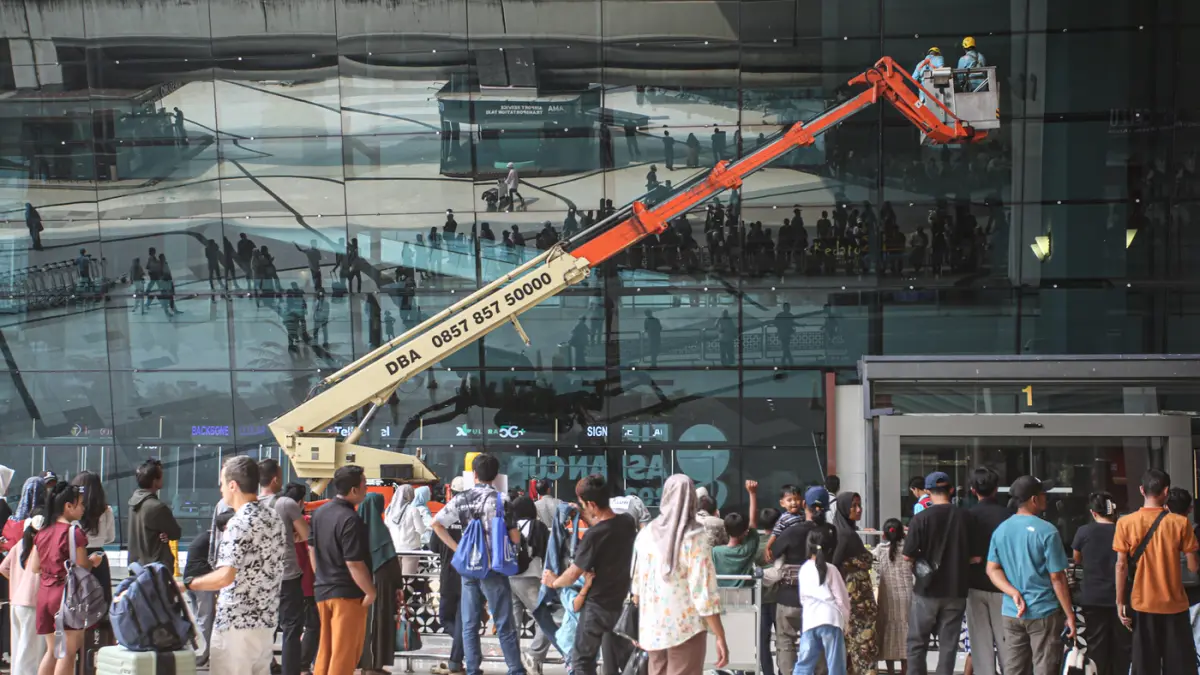 Pekerja gedung membersihkan kaca fasad menggunakan crane di Terminal 3, Bandara Soekarno-Hatta, Tangerang, Rabu (23/09/2026). (Hanung Hambara/ Jawa Pos)