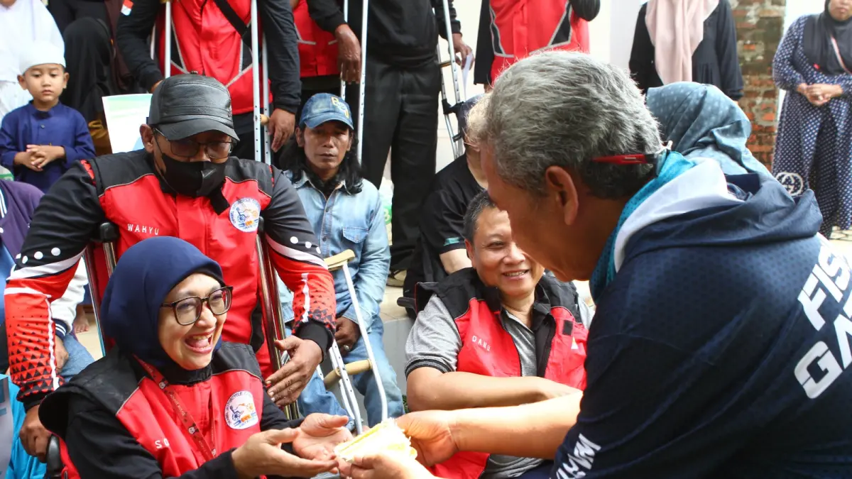 Ketua WMI, Firman Wibowo memberikan kue ulang tahun kepada salah satu anggota komunitas Disable Motorcycle Comunity (DMC) seusai acara pelatihan budidaya ikan air tawar kepada mereka dalam rangkaian hari jadi ke 9 WMI di Pemancingan Ayam Jago, Desa Mekarw