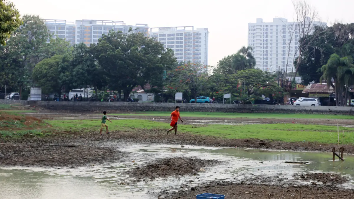 Anak-anak berjalan di antara tanah yang retak akibat mengeringnya Danau Cinere di Depok, Jawa Barat, Selasa (23/9/2026). (Dery Ridwansah/ JawaPos.com)
