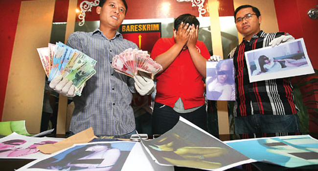 BOS PROSTISTUSI ONLINE: Papi Piesank menutup wajah saat ditunjukkan kepada media di Polrestabes Surabaya, Jawa Timur Minggu (17/8) lalu. - Image