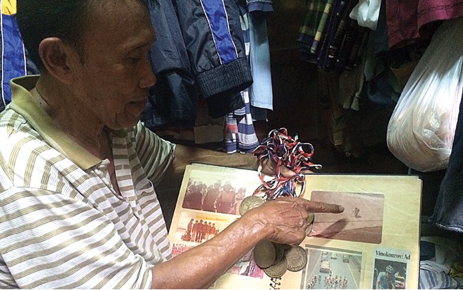 MASA TUA SURAM: Suharto menunjukkan album foto saat dirinya masih aktif dan sebagian medali yang diraihnya. - Image