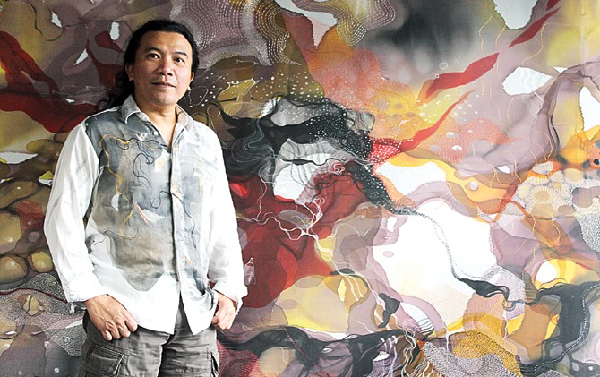 ISTIMEWA: John Martono menunjukkan lukisan dengan media kain sutra di John Martono’s Art Studio, Bandung, Senin pekan lalu (30/1). Dia juga mengenakan baju berbahan kain sutra lukisannya. - Image