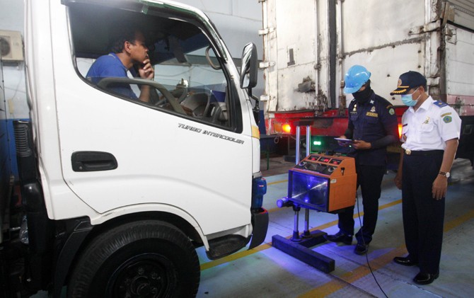 MENYALA TERANG: Zaini, petugas dishub bagian uji lampu, mengecek kualitas lampu truk dalam rangkaian uji kir Senin (13/2) di kantor dishub, Jalan Raya Candi, Sidoarjo. (Boy Slamet/Jawa Pos) - Image