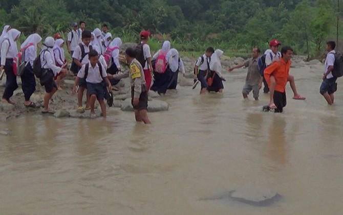 Akibat jembatan runtuh diterjang banjir, para pelajar Desa Nunuk Baru, Kecamatan Maja, Kabupaten Majalengka nekat menyeberangi Sungai Cisuluheun. - Image