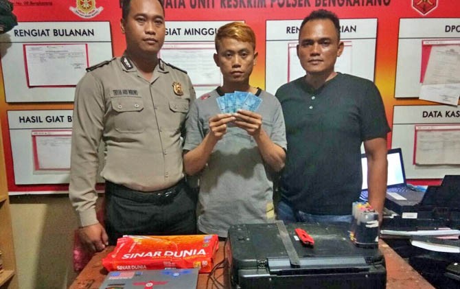Polisi memperlihatkan tersangka Teo (tengah) memegang barang bukti dan peralatan yang digunakannya untuk mencetak Upal di Mapolsek Bengkayang, Minggu (12/2). - Image