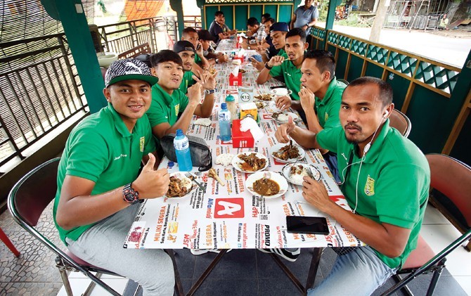 Aktivitas Mat Halil (kanan) di luar sebaga kapten tim Persebaya. Di antaranya menikmati sate klatak sebelum tampil dalam final turnamen prakompetisi Piala Dirgantara 2017. - Image