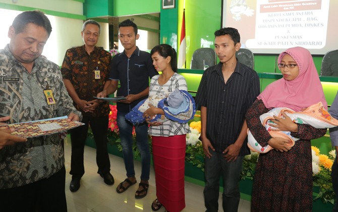 PERCONTOHAN: Asisten III Pemkab Sidoarjo Kisowo Sidi memberikan akta kelahiran kepada sejumlah orang tua Selasa (4/4) di Puskesmas Wonoayu. - Image