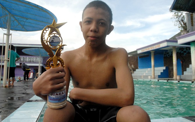 BIKIN KEJUTAN: Daffa menunjukan piala yang diperolehnya di sela-sela latihan di kolam renang Kebonagung, Sukodono, Sabtu (6/5). - Image