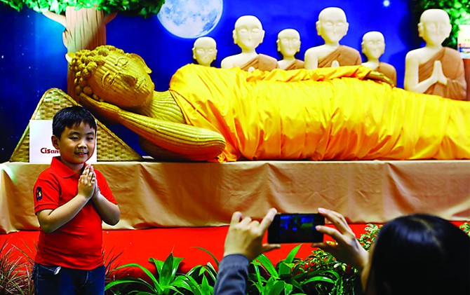 KENANG SANG BUDDHA: Felix Jiang difoto ibunya dengan latar belakang replika patung Buddha yang terbuat dari rotan pada Festival Waisak 2017, Rabu (10/5) di Tunjungan Plaza, Surabaya. - Image