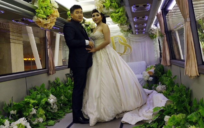 PIONER: Pasangan Denny Primaditya dan Stephanie Emanuella Salim melangsungkan pernikahan menggunakan bus pariwisata yang dimodifikasi melewati Raya Darmo menuju gedung resepsi. - Image