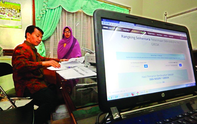 VERIFIKASI: Sekretaris PPDB SMAN 1 Gresik Mohammad Alil Himmah mempersiapkan berkas pendaftaran siswa. - Image