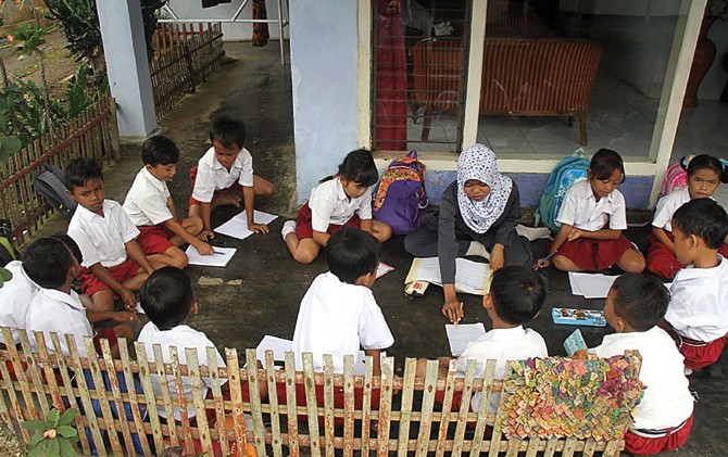 LESEHAN: Bu Wahyu, guru kelas II SDN Jambesari 02, Sumberbaru, Jember terpaksa mengajar siswa di teras rumah milik Rosida dengan cara lesehan. - Image