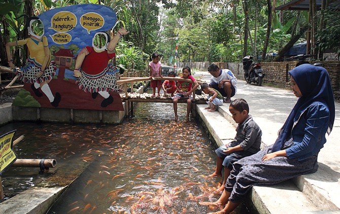 MENYENANGKAN: Warga menikmati rekreasi di saluran air yang berisi ribuan ikan. - Image