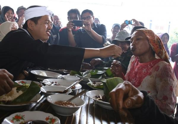 Bupati Purwakarta menyuapi warga ketika blusukan belum lama ini. Diusungnya Ridwan Kamil oleh Golkar, berpotensi hijrahya Dedi ke partai lain - Image
