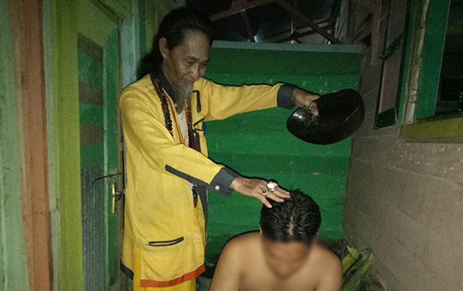 Salah satu warga sedang dimandikan oleh Abang Gunung - Image