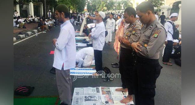 Peserta Aksi Bela Islam saat salat asar berjamaah dengan anggota kepolisian di Jalan Veteran, Jakarta Pusat, Jumat (4/11). - Image