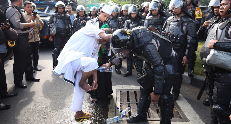 SIMPATIK: Seorang anggota polisi antihuru-hara membantu pengunjuk rasa yang berwudu untuk salat Asar di depan Istana Merdeka, Jakarta, kemarin (4/11). - Image