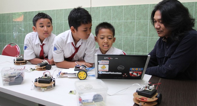 AKRAB DENGAN TEKNOLOGI: Dari kiri, Raffi Akmal, Darnel Faza, Achmad Riza, dan Dhadhang Setiabudi Winarto, guru pembimbing ekskul robotik SD Muhammadiyah 1 Sidoarjo, sedang mengutak-atik beberapa robot. - Image