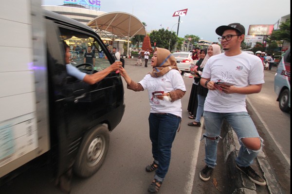 Relawan Baraja Foundation membagikan bunga kepada pengendara di Jl Tentara Pelajar, Kamis (1/12). Kegiatan ini dilaksanakan untuk memperingati Hari AIDS Sedunia. - Image