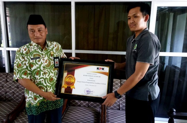 PIAGAM: Abdurahman Muhammad Bakri (kanan) menunjukkan piagam dari KPK lantaran rajin melaporkan gratifikasi, Jumat (23/3). - Image