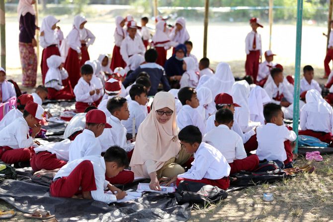 HARI PERTAMA SEKOLAH: Sulihi, mengajar muridnya di sekolah darurat buatan warga di lapangan pengungsian Desa Duman, Kecamatan Lingsar, Lombok Barat, Senin (27/8). Hari pertama sekolah pascagempa masih dilaksanakan di luar gedung. - Image