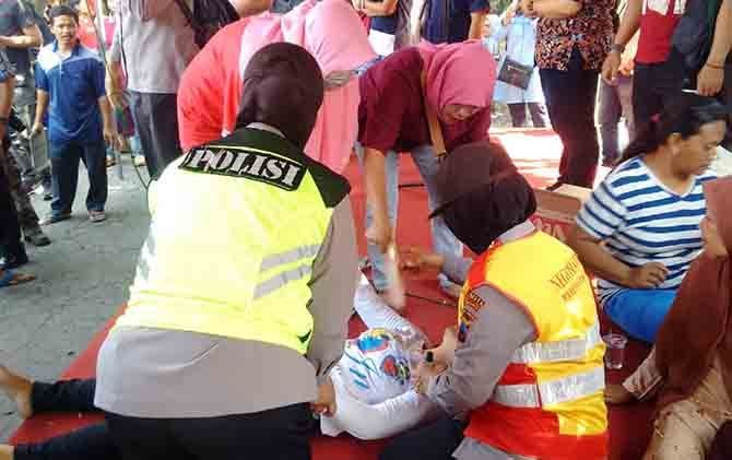 PINGSAN: Sejumlah petugas memberikan pertolongan kepada warga yang pingsan. - Image