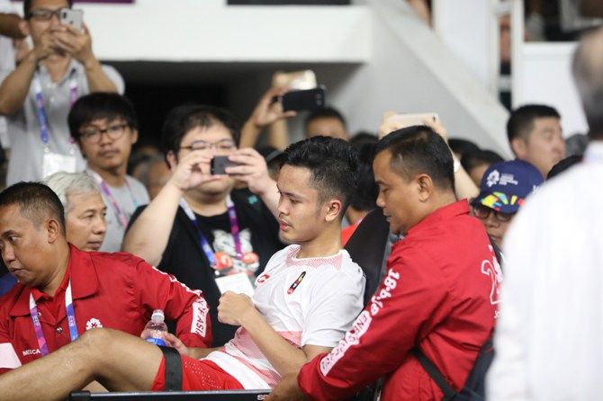 Anthony Sinisuka Ginting ditandu keluar arena setelah mengalami cedera di pertandingan pertama babak final beregu Asian Games 2018. - Image
