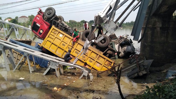 EVAKUASI: Sejumlah pekerja tengah melakukan evakuasi truk yang terperosok di jembatan Widang yang ambruk. - Image