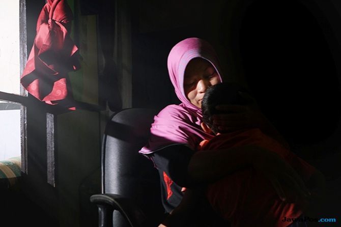 Baiq Nuril Maknun memeluk anaknya di kediamannya di Karang Bongkot, Kecamatan Labuapi, Lombok Barat, kemarin (15/11). Kasus ini tidak hanya mengancam Nuril masuk ke penjara, namun ikut menyeret anak anaknya menjadi korban. - Image