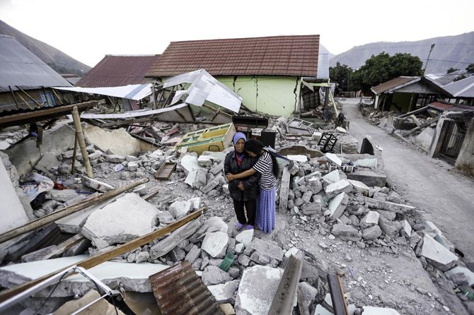 Seorang perempuan memeluk ibunya di tengah reruntuhan rumahnya di Sembalun Bumbung, Kecamatan Sembalun, Lombok Timur, Senin (20/8). Rumah mereka hancur setelah berkali kali diguncang gempa berkekuatan cukup besar. - Image