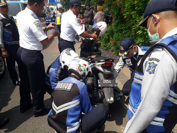 Petugas Dishub Surabaya menggembok salah satu kendaraan wali siswa SDN Kaliasin 1 yang terbukti melanggar saat parkir sembarangan. - Image
