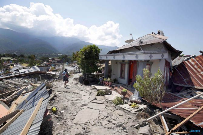 Warga melintas di perumnas balaroa yang terdampak gempa, Palu, Sulawesi tengah, Senin (1/10/2018). Gempa berkeuatan 7,4 skala richter tersebut menghancurkan rumah warga dan warga terpaksa mengungsi ketempat yang lebih aman. - Image