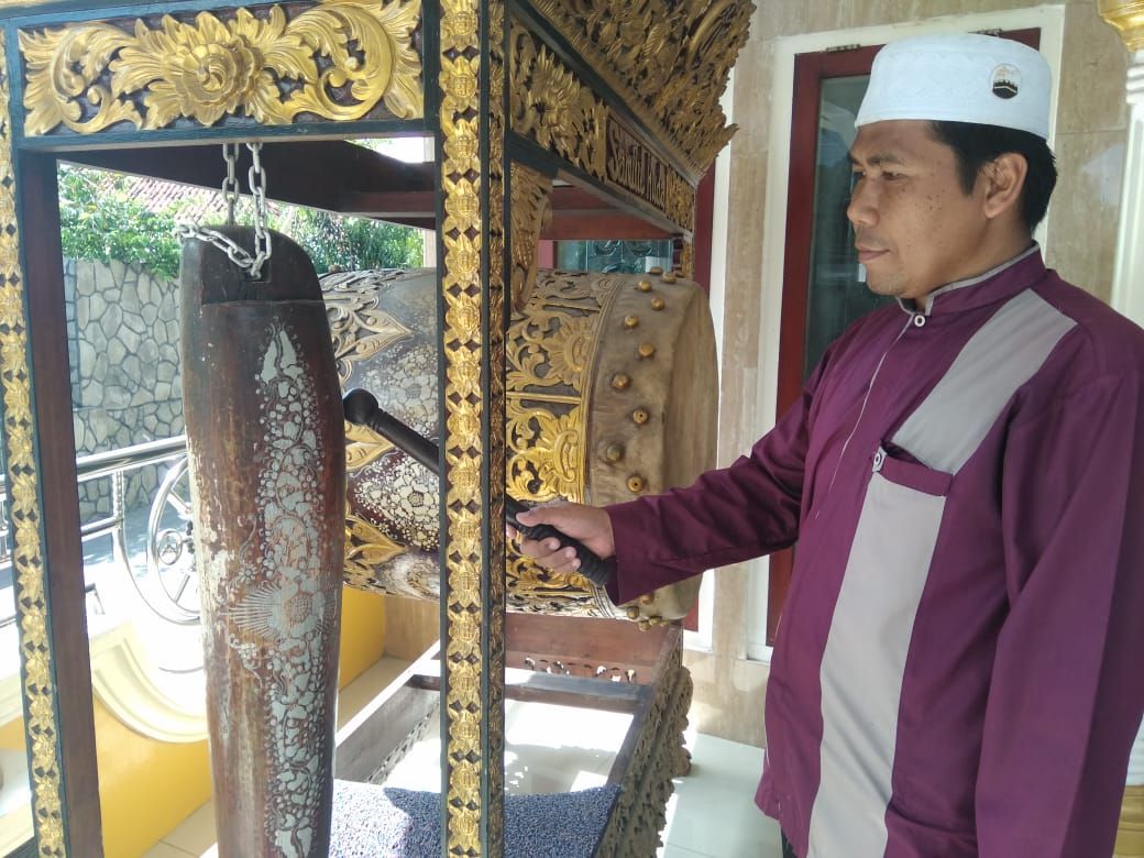 Ibrahim tengah memukul bedug tanda memasuki waktu salat. - Image
