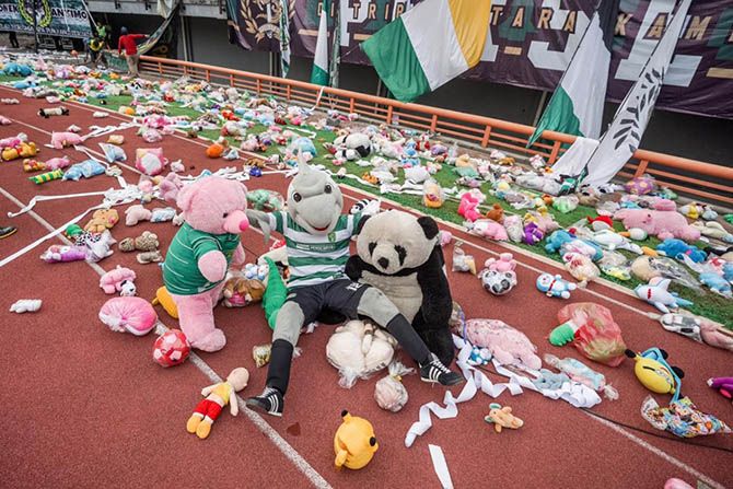Maskot Persebaya duduk bersama ribuan boneka di Stadion GBT, Jumat (29/3). - Image