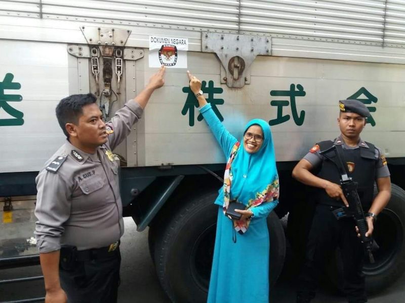 Ketua KPUD Kulonprogo, Mutia berfoto bersama polisi yang mengawal kontainer berisi surat suara - Image
