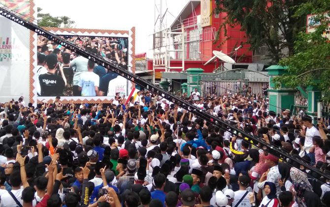 Sejumlah warga Palembang tampak mengacungkan dua jari saat Presiden Joko Widodo meminta tunjuk tangan di acara Milenial Road Safety Festival di Palembang, Sabtu (9/3). - Image