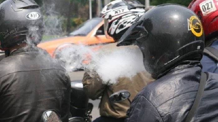 Pengendara motor merokok sambil mengemudi - Image