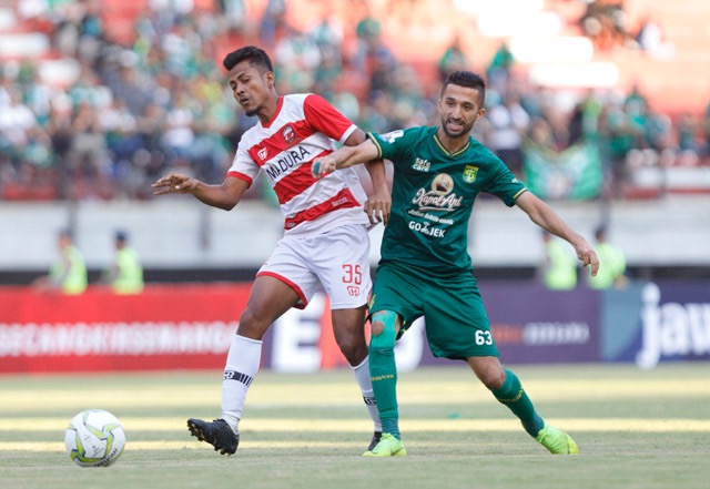 Gelandang Persebaya Manuchekhr Dzhalilov (kanan) mendapatkan pengawalan ketat dari pemain tengah Madura United Zulfiandi pada leg pertama babak perempat final Piala Indonesia di Stadion Gelora Bung Tomo, Surabaya, tadi sore. (Angger Bondan/Jawa Pos) - Image